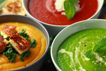 Variety of cream soup bowls: sweet pea and mint, tomato and basil and butternut squash with steamed...