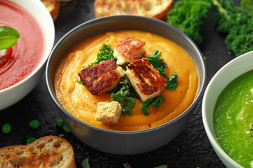 Variety of cream soup bowls: sweet pea and mint, tomato and basil and butternut squash with steamed kale and fried halluomi