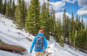 Tourist with backpack hiking on snowy trail