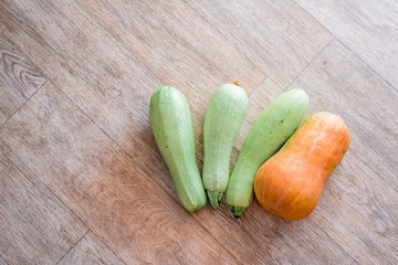 .three zucchini and one pumpkin on wooden texture background.