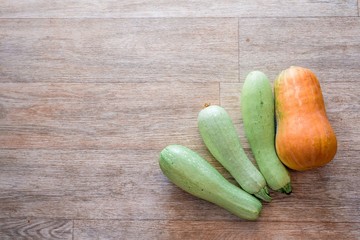 three zucchini and one pumpkin on a wooden texture background in the lower right corner