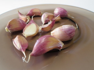 Untreated garlic cloves in brown plate close-up
