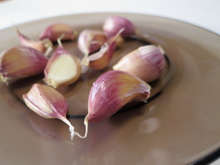 Untreated garlic cloves in brown plate close-up