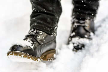 Black boots in snow, person put the step in snow, walking in winter