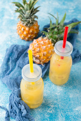 Fresh pineapple juice and ripe pineapple on grey background