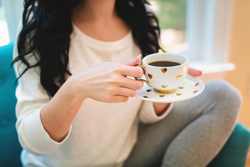 Young woman holding a cup of coffee in a chair in her home