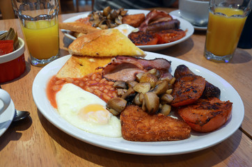 Complete english breakfast for two, with fried eggs, toast, mushrooms,tomato, sausage, beans hash browns and orange juice