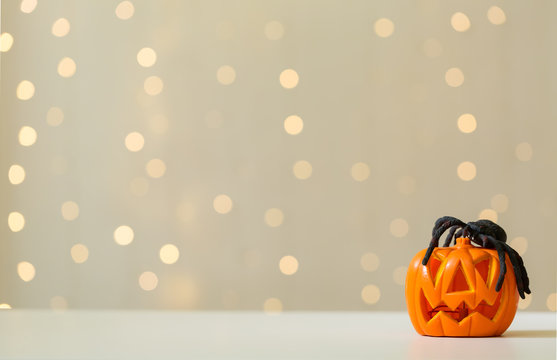 Halloween pumpkin with spider on a shiny light background