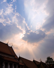 Fototapeta na wymiar Sun beam behind the sunset clouds over the buddhist temple