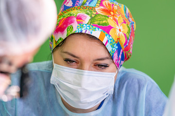 female surgeon doctor wearing protective mask and hat during the operation. Healthcare, medical education, emergency medical service, surgery concept.