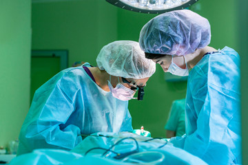 Surgeon and his assistant performing cosmetic surgery on nose in hospital operating room. Nose...