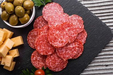 delicious sliced salami on a stone plate wooden background
