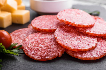 delicious sliced salami on a stone plate wooden background