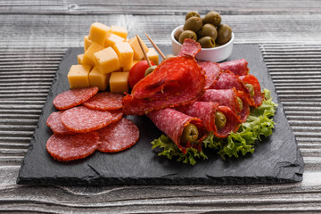 delicious sliced salami on a stone plate wooden background