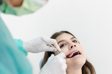 Dentist removing tooth of female young patient