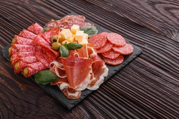 Cold smoked meat plate on a rustic wooden background