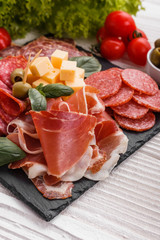 Cold smoked meat plate on a rustic wooden background