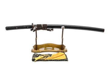Brown leather cord Japanese sword with black scabbard  on wooden stand and  bag in front of, isolated in white background.