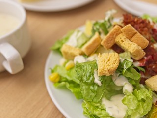 Mix salad that consists of mixed vegetables fruits and meats in white plate on wooden table