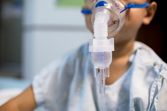 Little boy using inhaler Inhaling through oxygen mask.