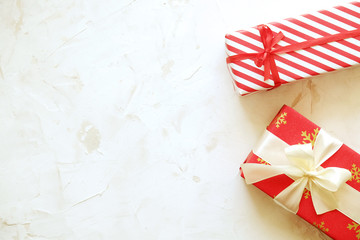 Fototapeta premium Two christmas presents wrappend in red and white paper tied with wide & thin silk bows. Multiple new years gifts in different wrapping. Top view, close up, copy space, background, flat lay