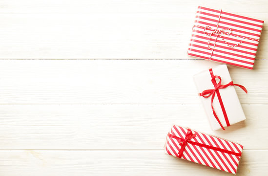 Three christmas presents wrappend in red and white paper tied with baker's twine string & silk bow. Multiple new years gifts in different wrapping. Top view, close up, copy space, background, flat lay
