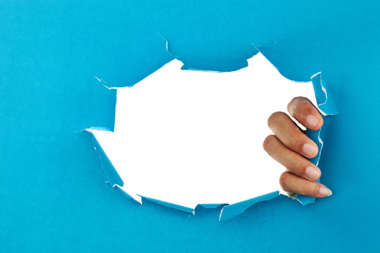 male hand ripped blue paper on white background,space for your message on torn paper.