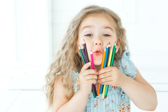 Portrait of cutew little girl holding pencils