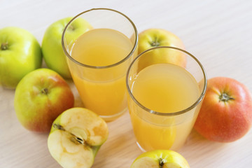 two glasses of juice, Apple juice, whole apples and apples cut in half
