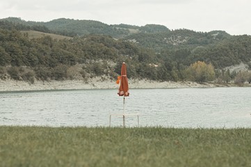 Isolated red beach umbrella on the shore of Fiastra Lake, Marche, Italy, Europe