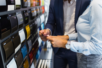 Young handsome man talking with saleswoman and choosing a color for his new car at car showroom.