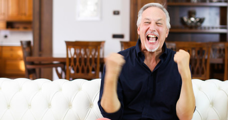 Ecstatic man exultating while watching a match at the tv