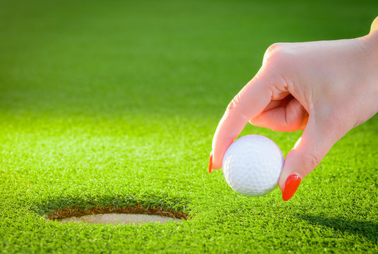 golfball regarded a woman's hand to the hole