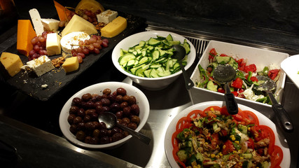 Greek salads, olives, sliced cucumbers and various cheeses.