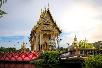 Obraz premium The Thai temple in Wat Plai Laem in Samui Island Thailand, in the middle of the water, contains giant statues and elephants.Pigeon flies through.