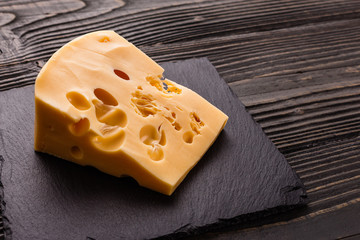 Piece and slices of cheese on a wooden background