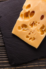 Piece and slices of cheese on a wooden background