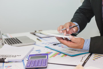 Close up businessman using tablet in the calculations revenue and market statistics.