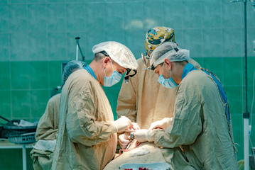 three doctors conduct a patient operation with the participation of a nurse in the operating room in the hospital. Close-up