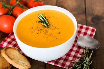 Squash Soup with Rosemary on rustic wooden table.  Autumn Pumpkin cream-soup in a white bowl  with croutons. Top view.