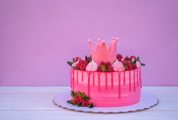 pink cake with crown on birthday on a lilac background