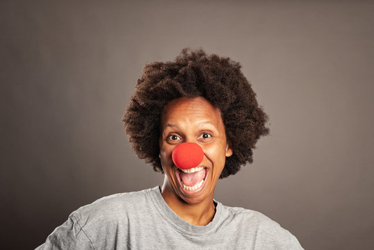 happy black woman with a clown nose on a gray background