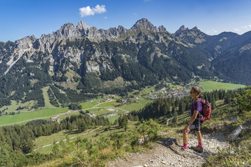 senior woman, hiking in a scenic mountain landscape in the Tannheim Valley, Tirol, Austria with the famous summits of Rote Flueh, Gimpel and Aggenstein