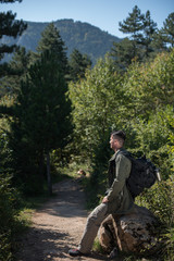hiker sitting on rock near the path to forest 