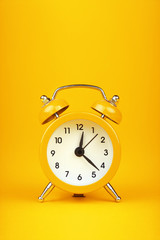 Close up one yellow alarm clock over warm yellow