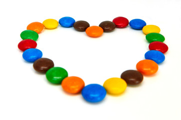 colorful chocolate buttons in the shape of heart on a white background