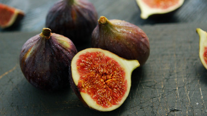 Arrangement of whole and cut fresh ripe figs with soft juicy flesh composed on rough wooden table