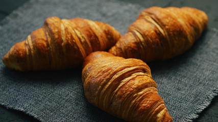 From above view of three fresh croissants laid on textile napkin 