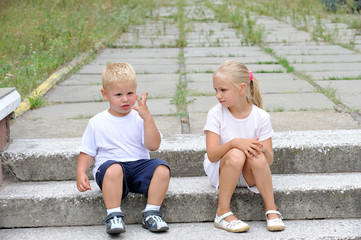 The girl and the boy are sitting on the steps in the парк