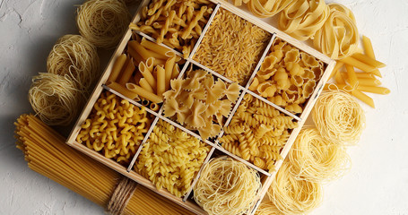 From above view of macaroni of different sort placed in dish with sections on white background
